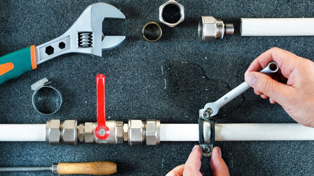 Plumber repairing a pipe valve with an adjustable wrench in Desert Hot Springs
